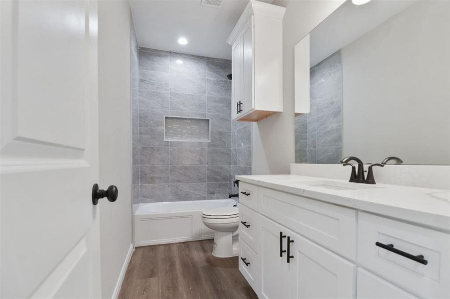 Full bathroom featuring vanity, toilet, wood-type flooring, and tiled shower / bath combo