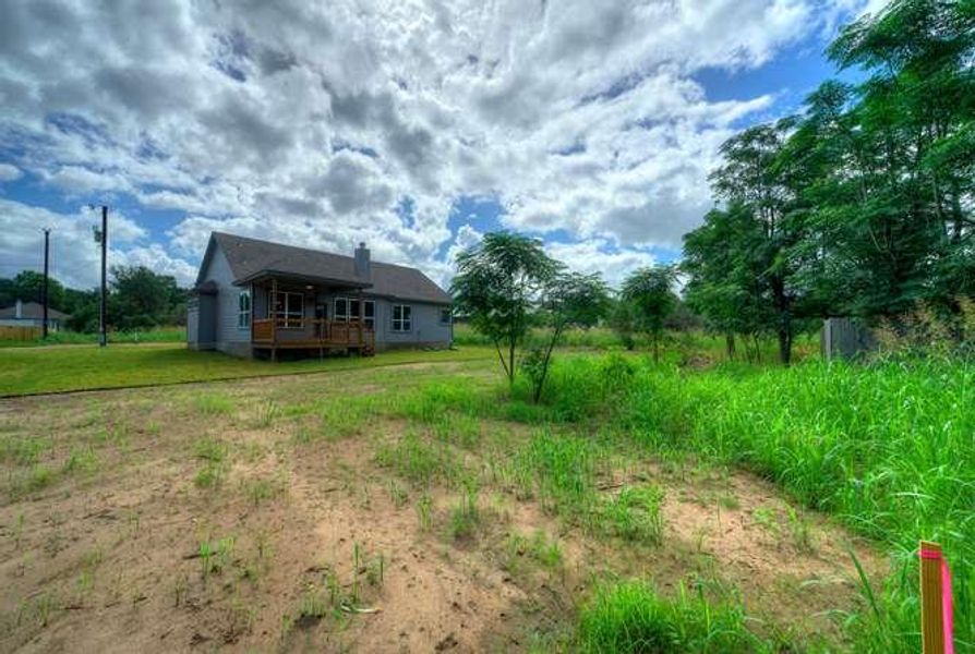 A quaint residence with a welcoming porch sits amidst a verdant landscape, perfect for serene living.
