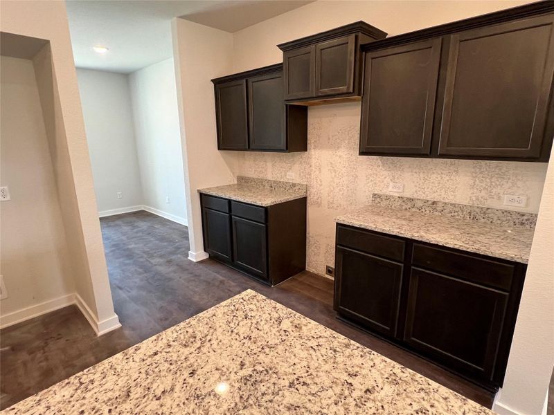 Kitchen with light stone countertops and dark brown cabinetry Kitchen with light stone countertops and dark brown cabinetry