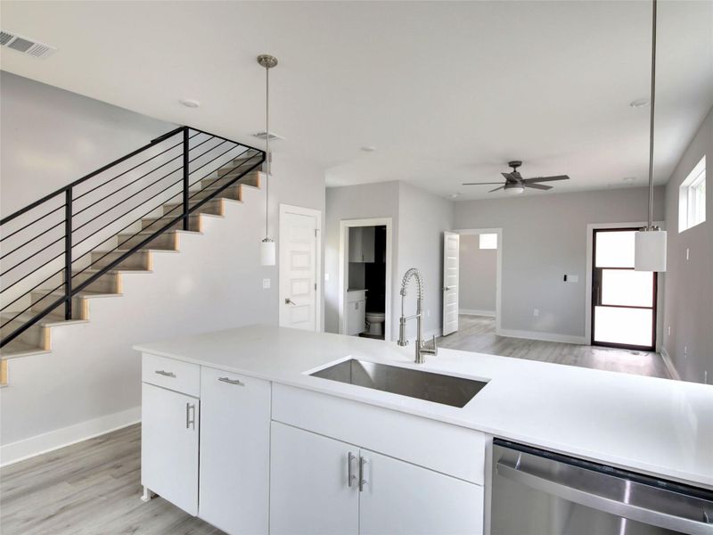 Kitchen featuring hanging light fixtures, dishwasher, white cabinetry, light wood-style floors, and a ceiling fan