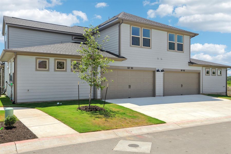 Traditional-style home with an attached garage, roof with shingles, and driveway