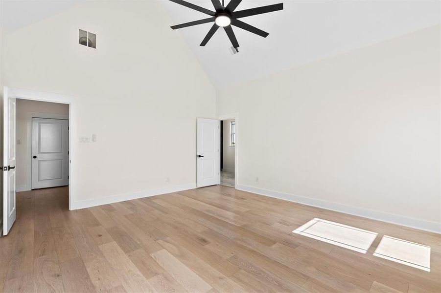 Spare room with high vaulted ceiling, a ceiling fan, baseboards, and light wood-style flooring Spare room with high vaulted ceiling, a ceiling fan, baseboards, and light wood-style flooring