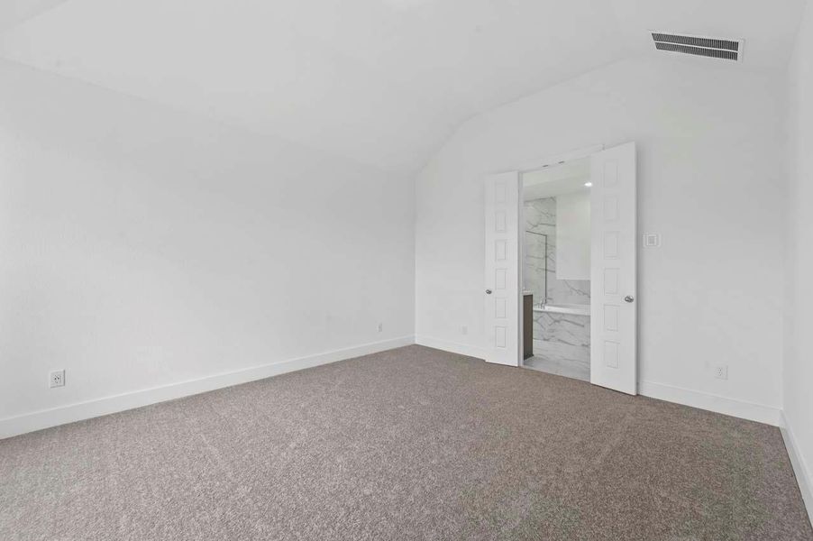 Unfurnished bedroom with carpet floors, visible vents, baseboards, ensuite bath, and vaulted ceiling