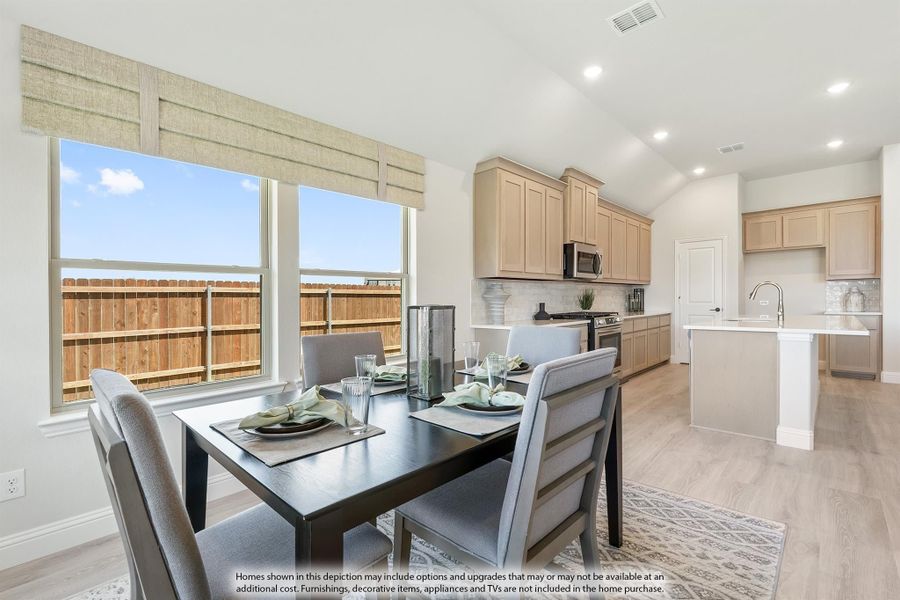Open dining area with dark wood table next to windows, connected to kitchen with light wood cabinets and center island