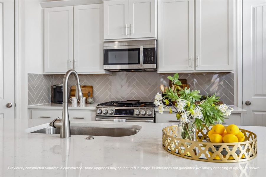 Timeless Functionality: The heart of the home shines with a single-bay undermount sink, sleek gooseneck faucet, and polished quartz countertops—paired with custom cabinets adorned with elegant hardware for a refined yet functional touch.