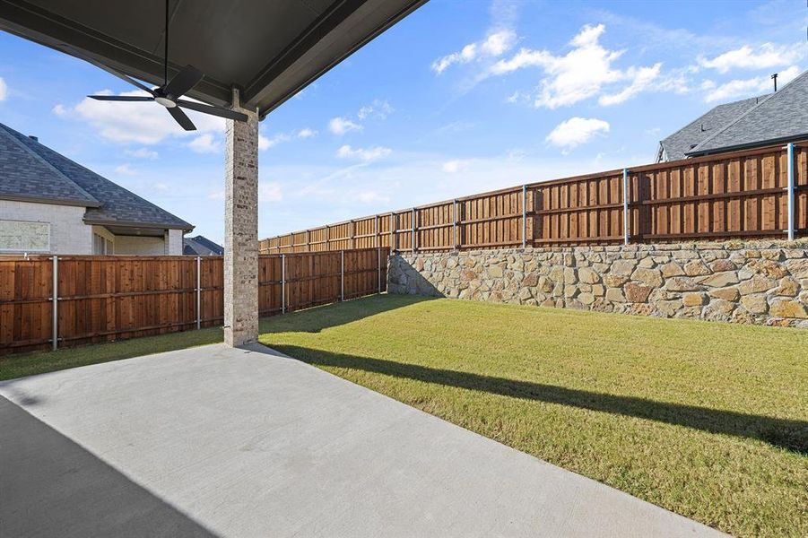 Fenced backyard with a ceiling fan and a patio area