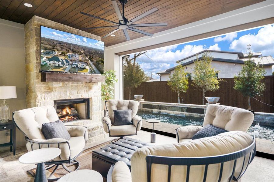 View of patio / terrace with ceiling fan and an outdoor stone fireplace.  Drop down shade that encloses the patio for indoor outdoor fun