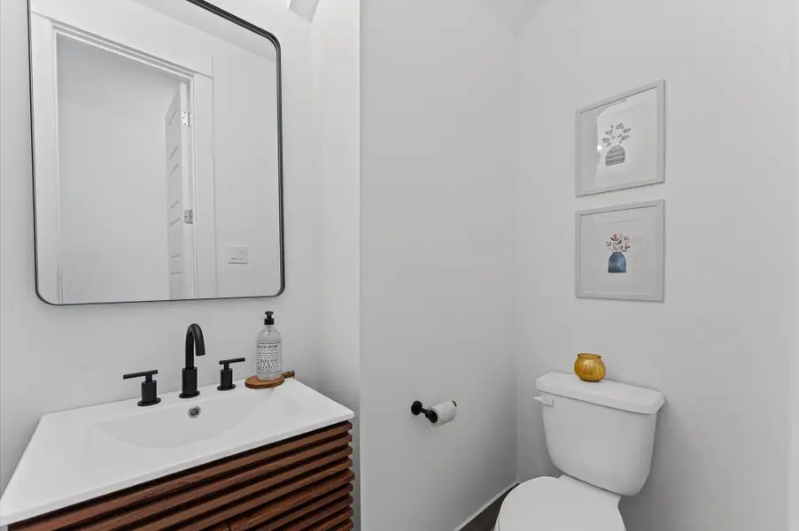 Tucked conveniently near the living area, this powder room blends accessibility with sleek contemporary style. Clean lines and modern fixtures define the space, from the minimalist vanity to the streamlined sink and faucet.