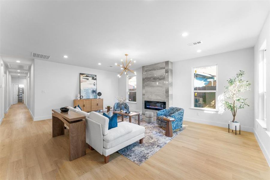 Living area featuring light wood-type flooring, a fireplace, and a chandelier