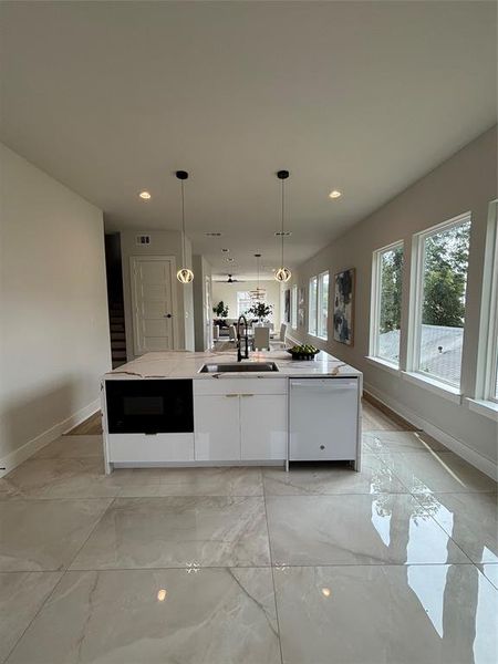 Kitchen with white cabinetry, light stone counters, dishwashing machine, hanging light fixtures, and recessed lighting