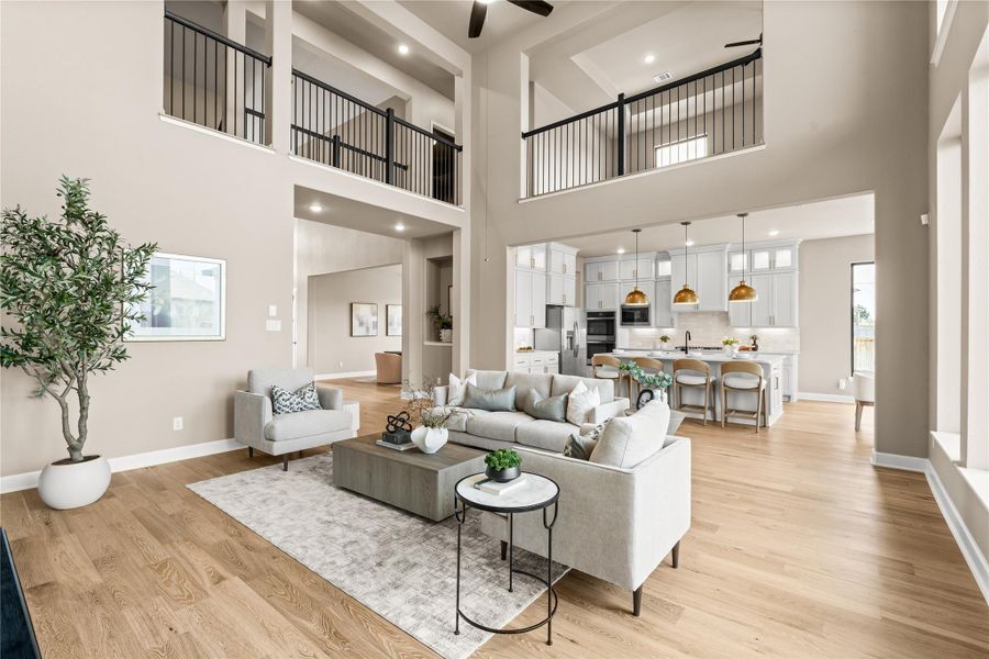 Spacious open-concept living area featuring high ceilings, elegant wood flooring, and a modern kitchen with sleek white cabinetry and stylish pendant lighting. *Virtually Staged*