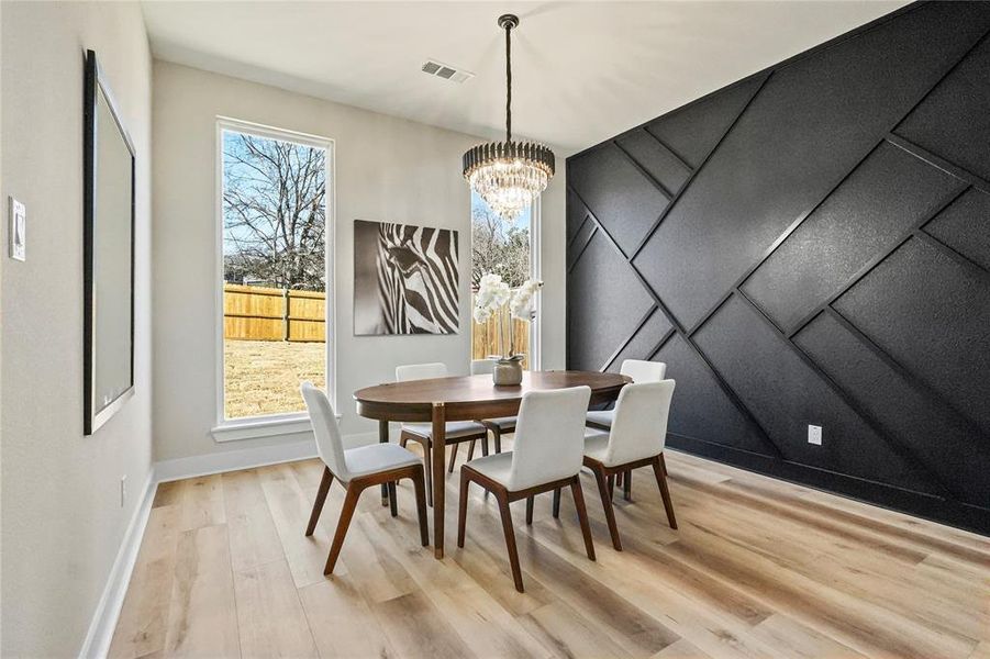 Dining room with a decorative wall, light wood-style floors, an accent wall, and a chandelier