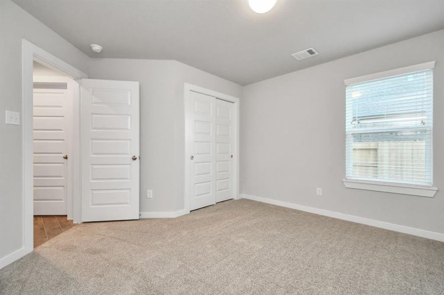 Generously sized secondary bedrooms featuring spacious closets, soft and inviting carpeting underfoot, large windows allowing plenty of natural light, and the added touch of privacy blinds for your personal retreat. Sample photo of completed home with similar floor plan. As-built interior colors and selections may vary.