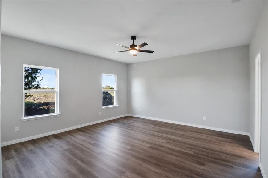 Empty room with ceiling fan and dark hardwood / wood-style floors