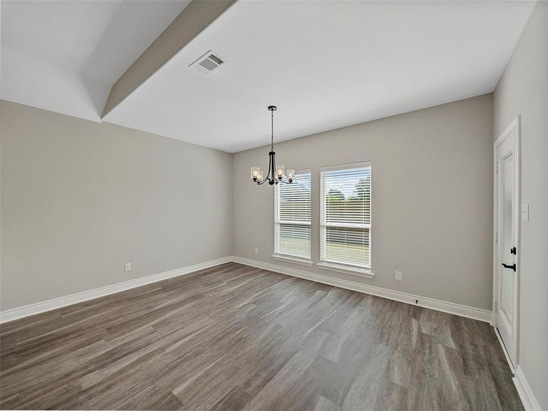 Unfurnished dining area featuring wood finished floors and a chandelier Unfurnished dining area featuring wood finished floors and a chandelier