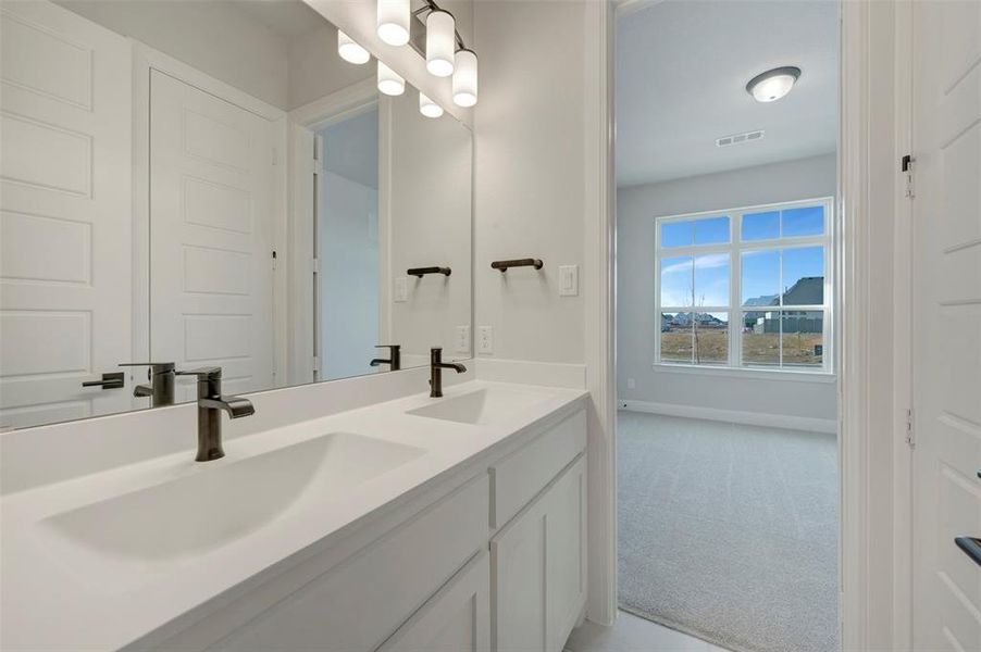 Bathroom with double vanity and light carpet