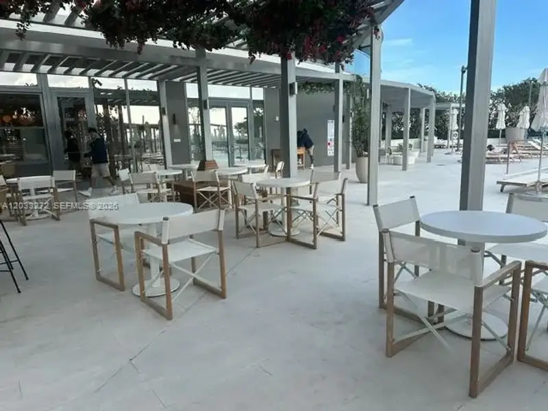 Expansive covered patio featuring light-toned tile flooring, structured metal framing, and extensive glass-paneled walls Expansive covered patio featuring light-toned tile flooring, structured metal framing, and extensive glass-paneled walls
