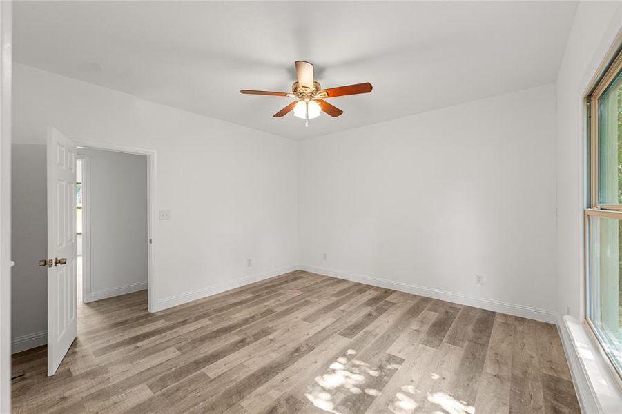 Unfurnished room with light wood-type flooring, plenty of natural light, and ceiling fan