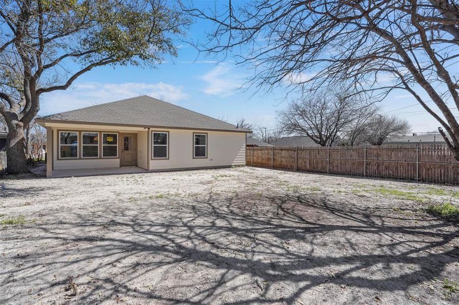 Rear view of house with roof with shingles and fence