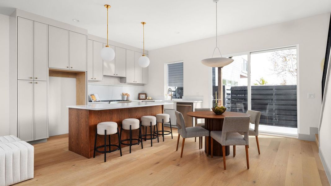 Kitchen with white cabinets, decorative light fixtures, a center island, and light wood-style floors