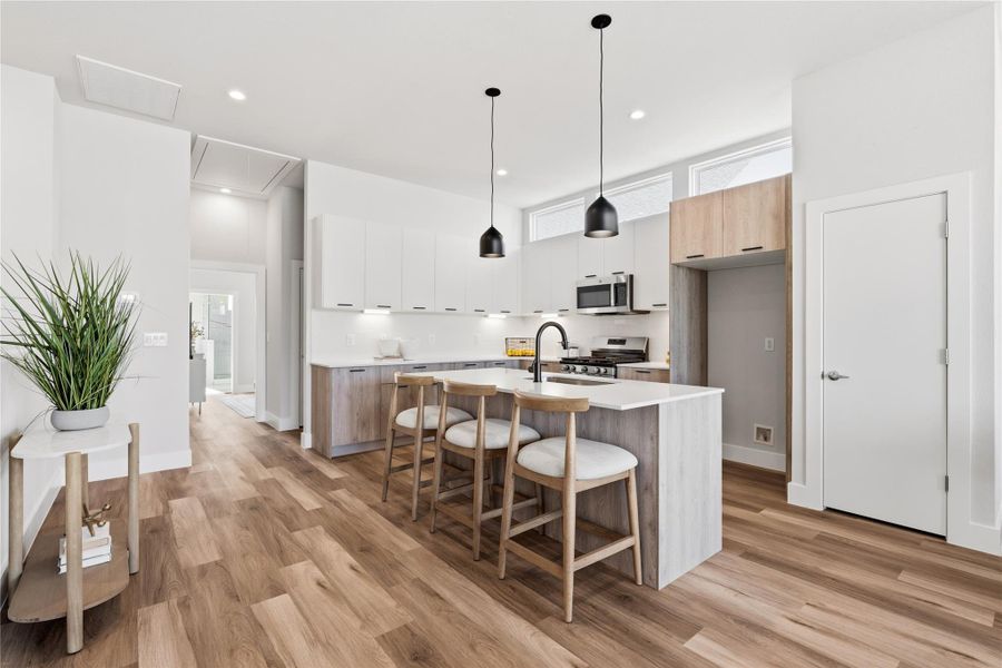 A discreet hallway pulls private spaces out of view, with the utility room and guest powder bath tucked away, while the primary suite sits quietly at the back of the home.