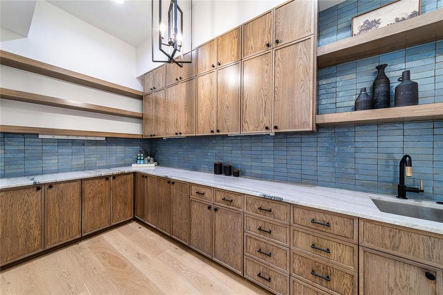 Kitchen featuring open shelves, backsplash, light wood-style flooring, and light stone counters