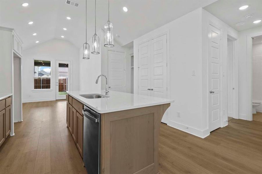 Kitchen with recessed lighting, dark wood finished floors, vaulted ceiling, pendant lighting, and a kitchen island with sink Kitchen with recessed lighting, dark wood finished floors, vaulted ceiling, pendant lighting, and a kitchen island with sink