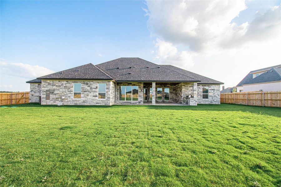 A spacious backyard with mature green grass and a covered patio, perfect for outdoor entertaining.
