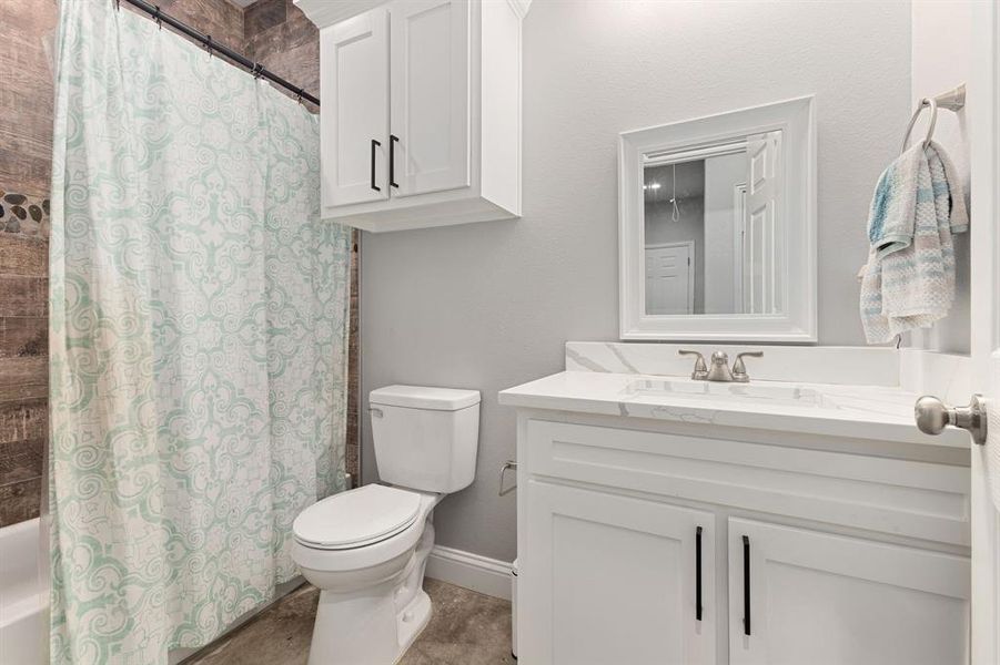 Full bathroom featuring shower / tub combo with curtain, vanity, and toilet