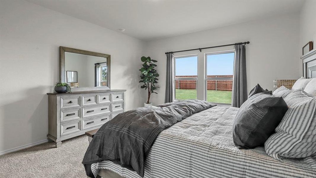 Bedroom featuring light colored carpet and multiple windows
