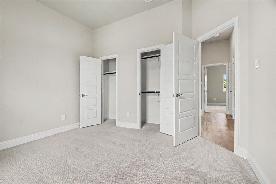 Carpeted room featuring two closets with white panel doors and chrome hardware Carpeted room featuring two closets with white panel doors and chrome hardware