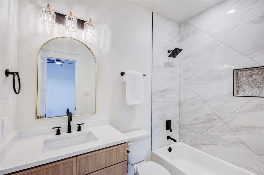 Full bathroom with ceiling fan, toilet, vanity, and tiled shower / bath combo