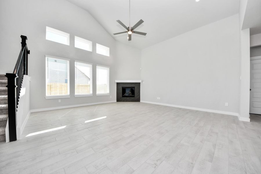 Welcome family and guests to your charming living room! With its high ceilings, recessed lighting, ceiling fan, custom paint, beautiful flooring, and large windows that let in abundant natural light, this room is perfect for gatherings. Sample photo of completed home with similar floor plan. Actual colors and selections may vary.