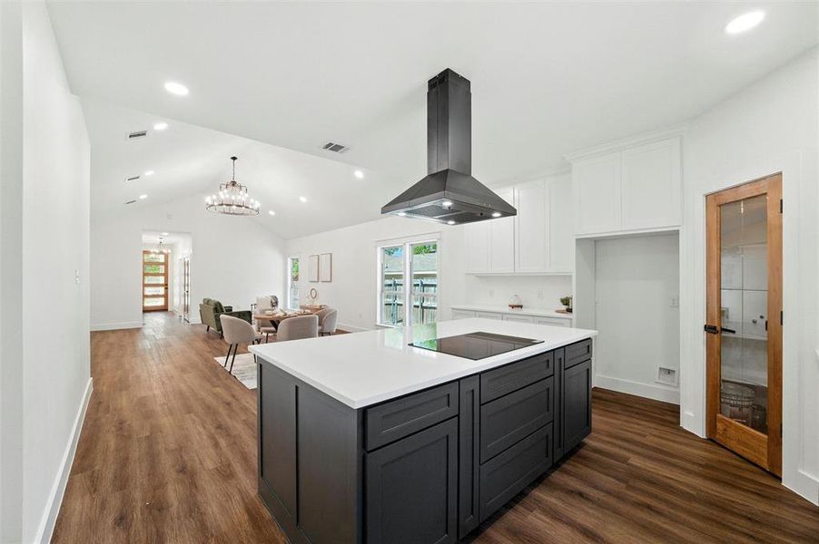 Kitchen featuring island range hood, white cabinetry, plenty of natural light, dark wood finished floors, and vaulted ceiling