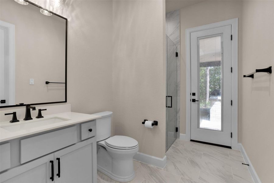 The full ensuite bath features awalk-in shower with directaccess to the backyard—makingit perfect for guests or as aconvenient pool bath.