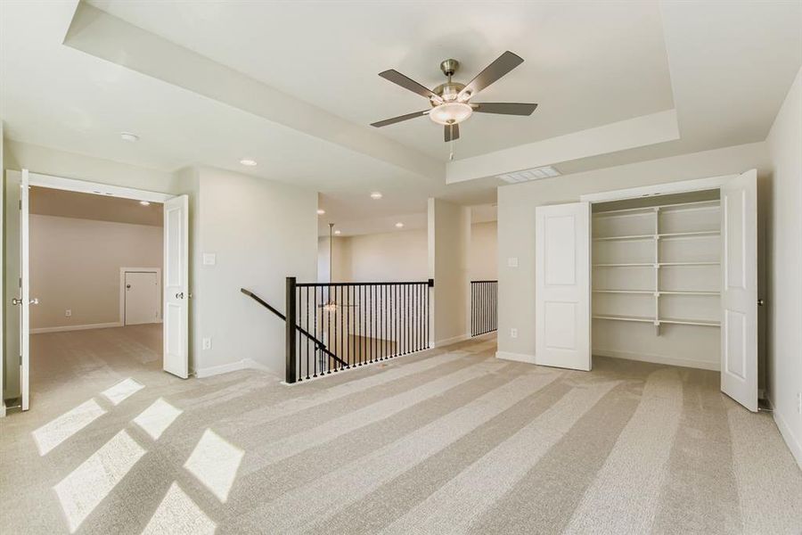 Unfurnished bedroom with a raised ceiling, light colored carpet, ceiling fan, recessed lighting, and a closet