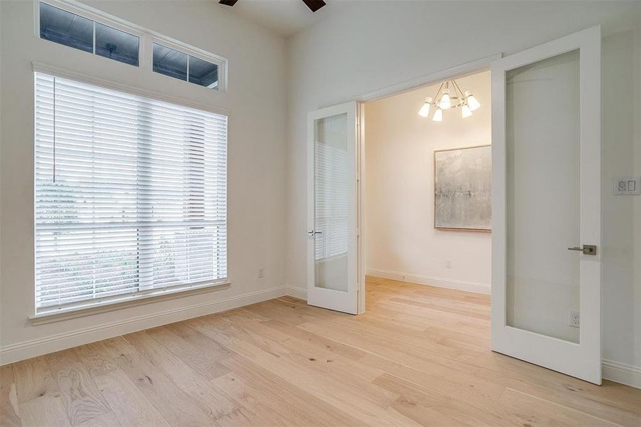 Large study featuring French doors with inlaid glass, ceiling fan and large window for natural lighting.