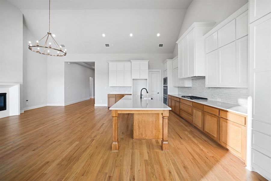 Kitchen with decorative backsplash, an island with sink, a breakfast bar, brown cabinets, and recessed lighting Kitchen with decorative backsplash, an island with sink, a breakfast bar, brown cabinets, and recessed lighting