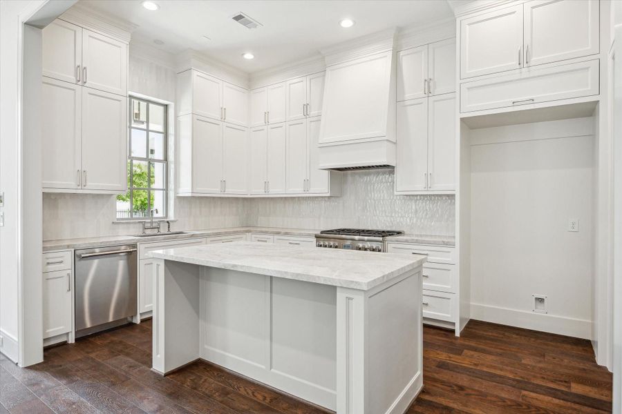 Kitchen features Thermador stainless steel appliances and Taj Mahal Polished Quartzite countertops.