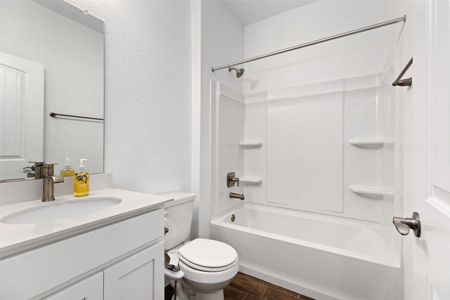 Full bathroom with vanity, bathing tub / shower combination, and a textured wall