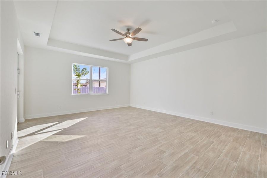 Unfurnished room featuring a tray ceiling, wood finish floors, and a ceiling fan