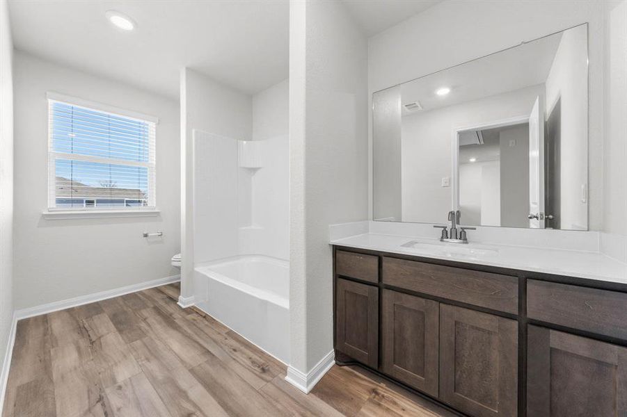 Full bathroom featuring hardwood / wood-style flooring, vanity, tub / shower combination, and toilet