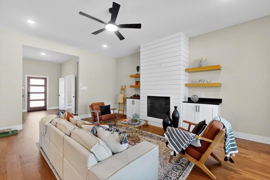 Living area featuring ceiling fan, wood finished floors, recessed lighting, and a large fireplace