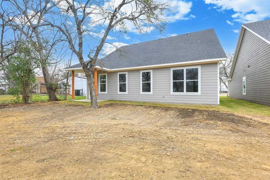 Rear view of house featuring a patio area and a shingled roof