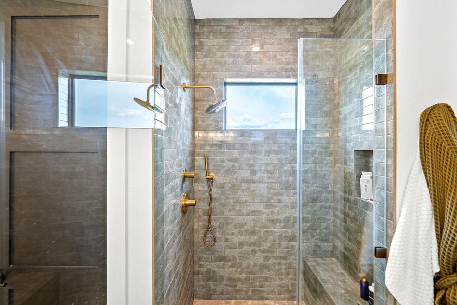 Glazed wall tiles and warm brass fixtures elevate this modern walk-in shower.