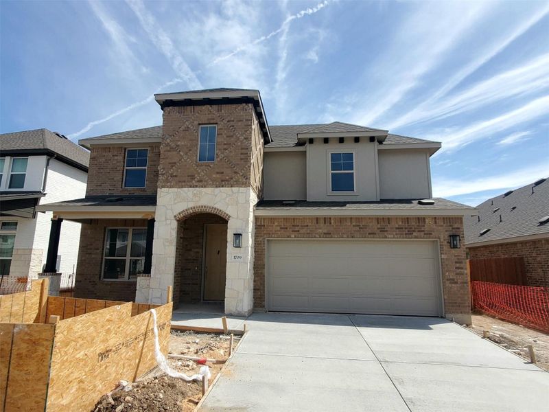 View of front of home with an attached garage, fence, roof with shingles, stone siding, and driveway