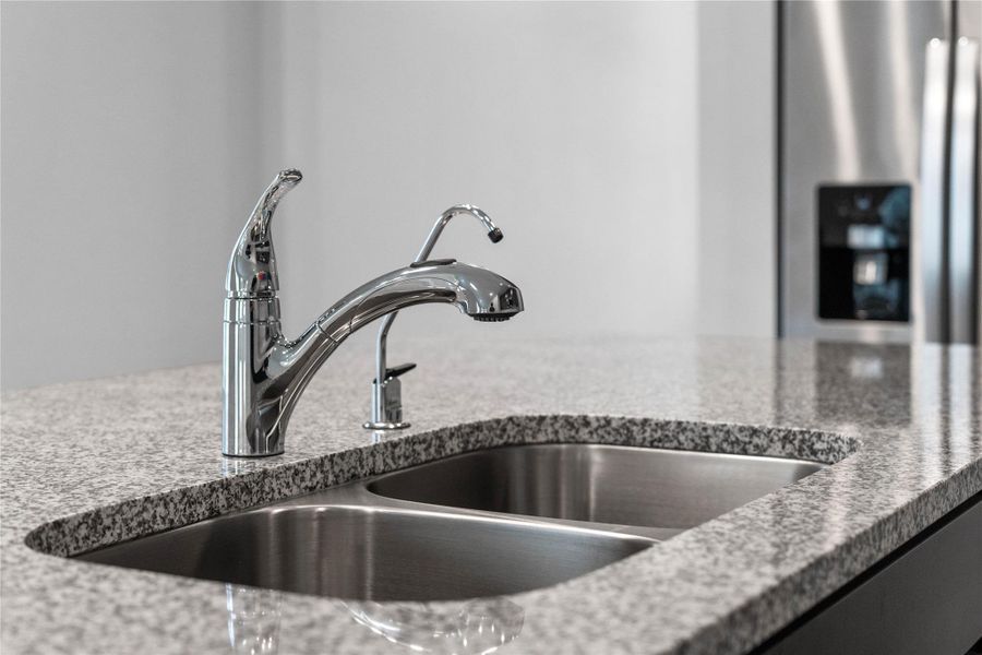 This modern kitchen island features a polished granite countertop with an undermount double-bowl stainless steel sink, complemented by a Moen Integra chrome kitchen faucet and DuPure filtered water tap.