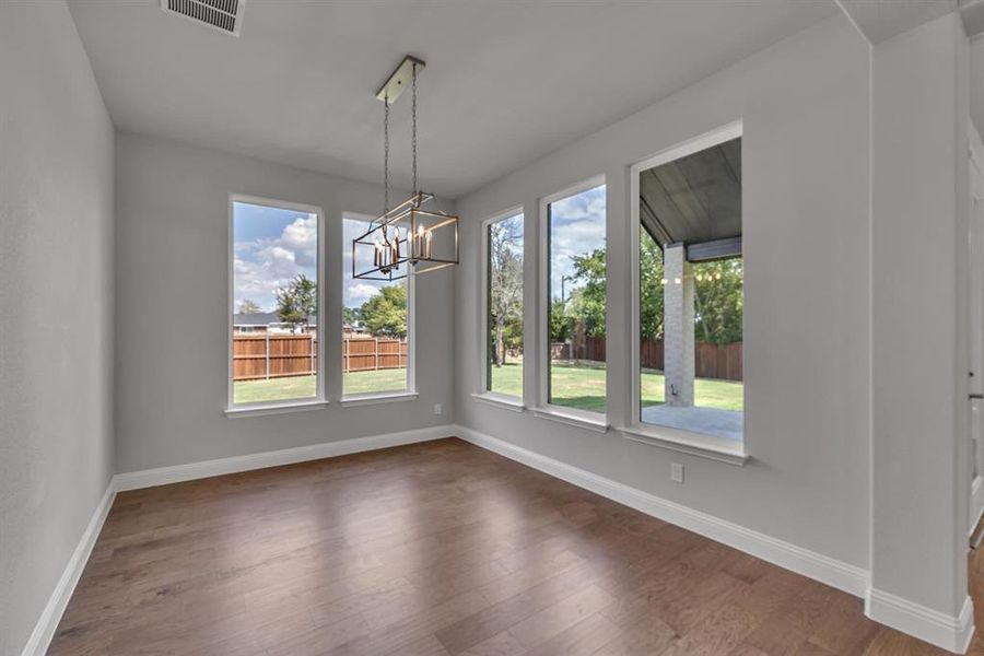 Unfurnished dining area with plenty of natural light, an inviting chandelier, and dark wood-type flooring