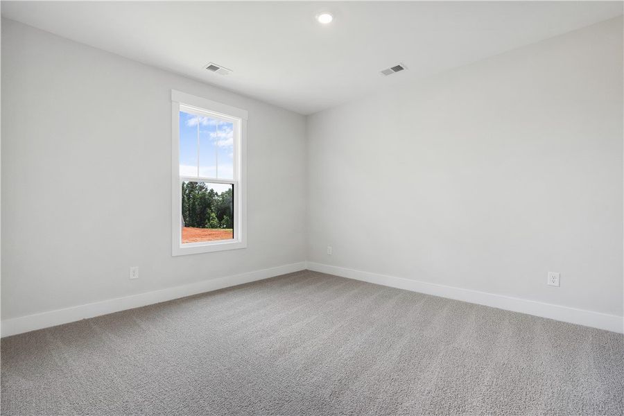 Well-lit room featuring soft gray carpeting and a Well-lit room featuring soft gray carpeting and a