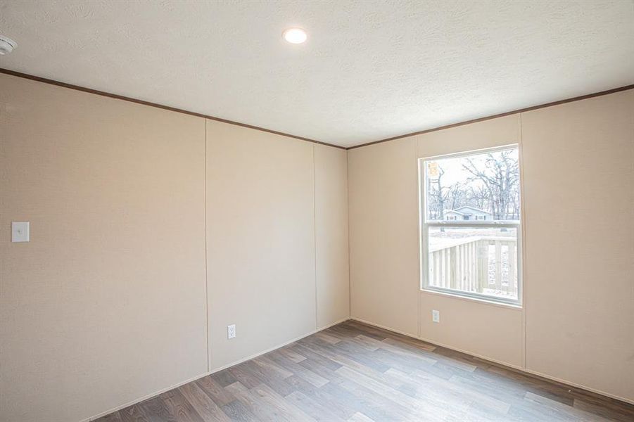 Unfurnished room featuring a textured ceiling and hardwood / wood-style flooring Unfurnished room featuring a textured ceiling and hardwood / wood-style flooring